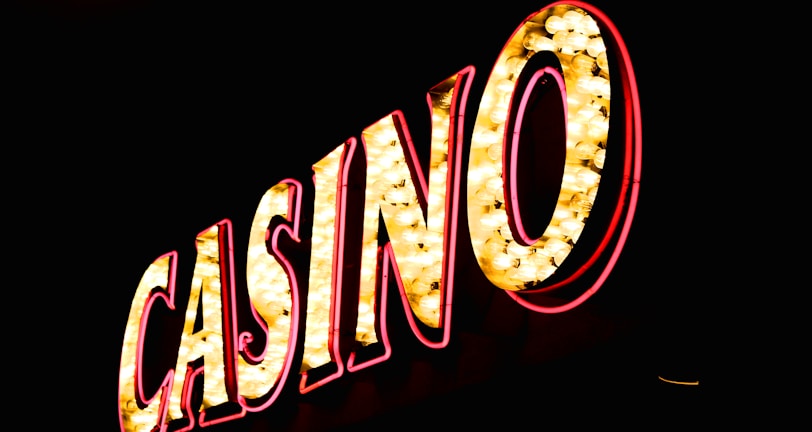 Brightly illuminated letters spell out 'CASINO' with glowing yellow bulbs and red outlines against a dark background.